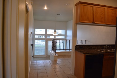 A kitchen with a black dishwasher and wooden cabinets.