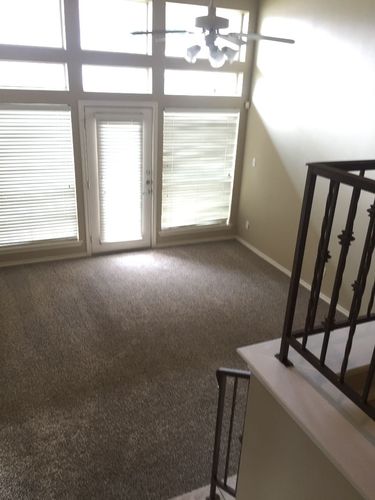 A room with a carpeted floor and a window with blinds.