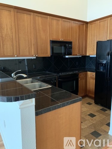 A kitchen with wooden cabinets and black appliances.