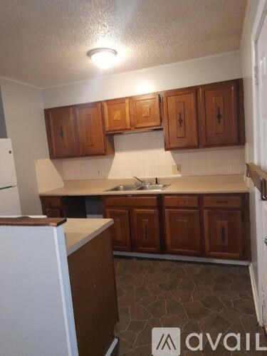 A kitchen with brown cabinets and a white refrigerator.