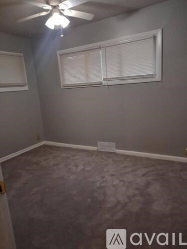 A room with a fan and a window with blinds.