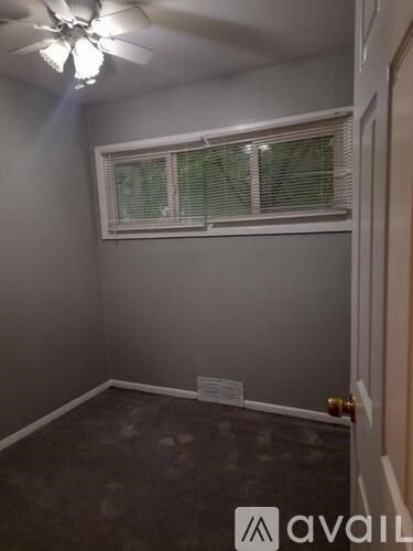 A room with a ceiling fan and a window with blinds.