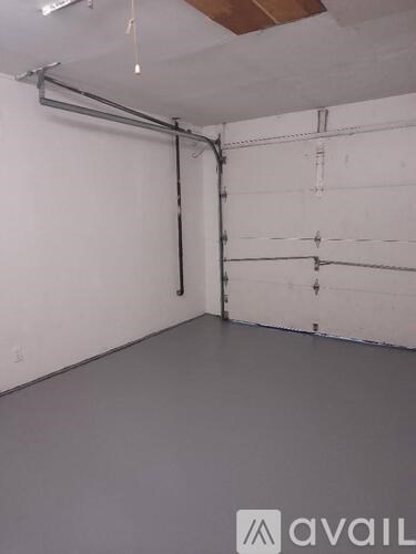 A large empty room with a white wall and a grey floor.