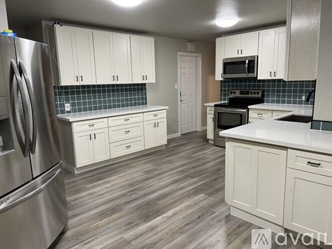 A kitchen with white cabinets and a stainless steel refrigerator.