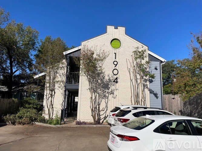A white car is parked in front of a building with the number 1904 on it.