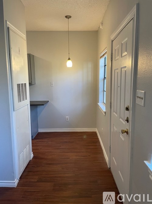 A hallway with a white door and a light hanging from the ceiling.