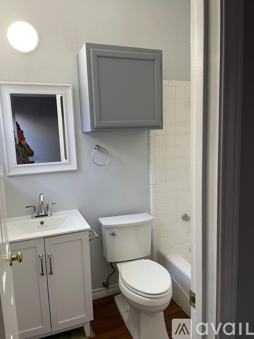 A bathroom with a toilet, sink, and mirror.