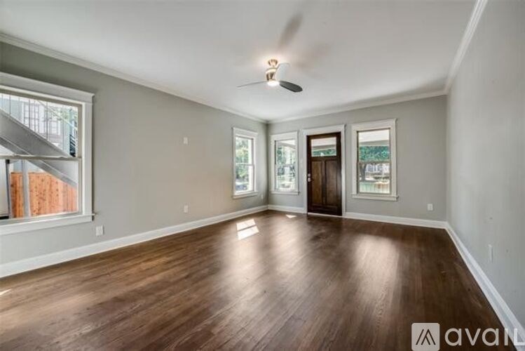 A spacious room with wooden floors and a ceiling fan.