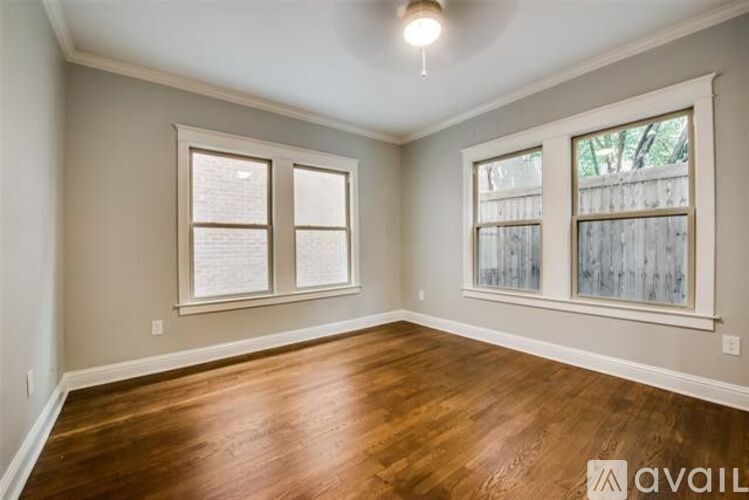 A room with wooden floors and two windows.