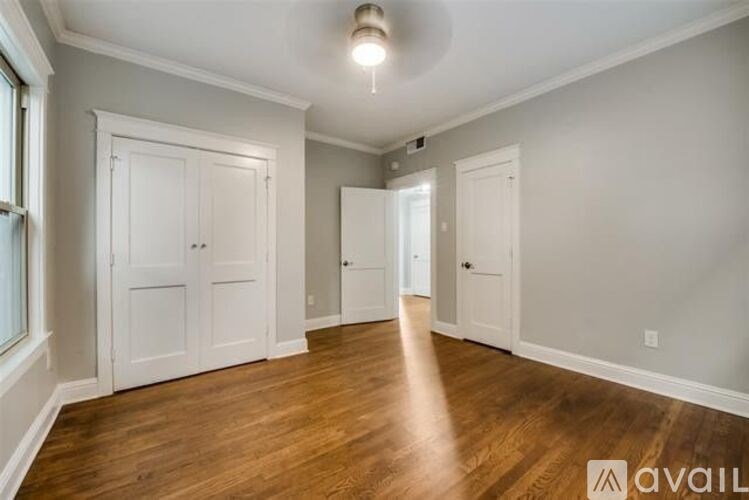 A spacious room with wooden floors and white doors.