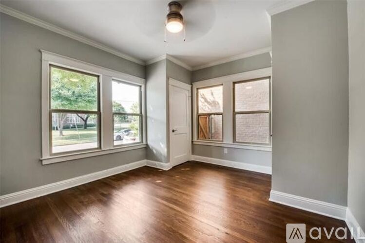A room with wooden floors and a window overlooking a street.