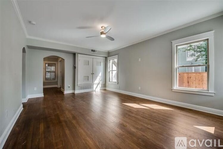 A spacious room with wooden floors and a ceiling fan.