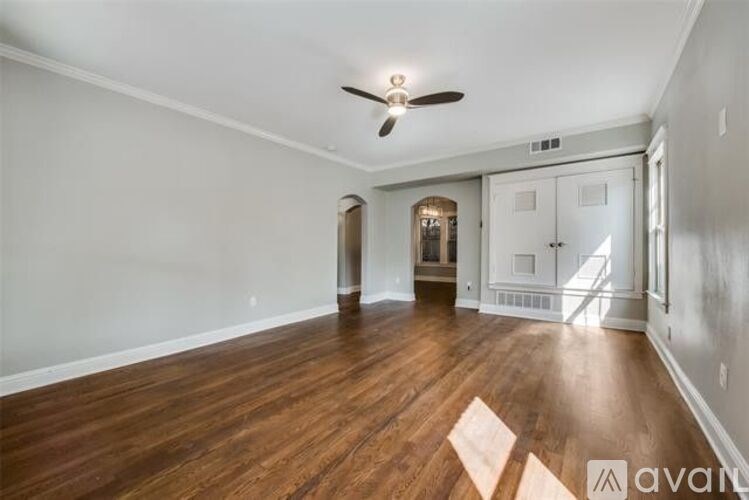 A spacious room with wood flooring and a ceiling fan.
