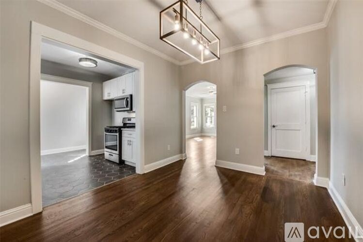 A spacious kitchen with white appliances and a wooden floor.