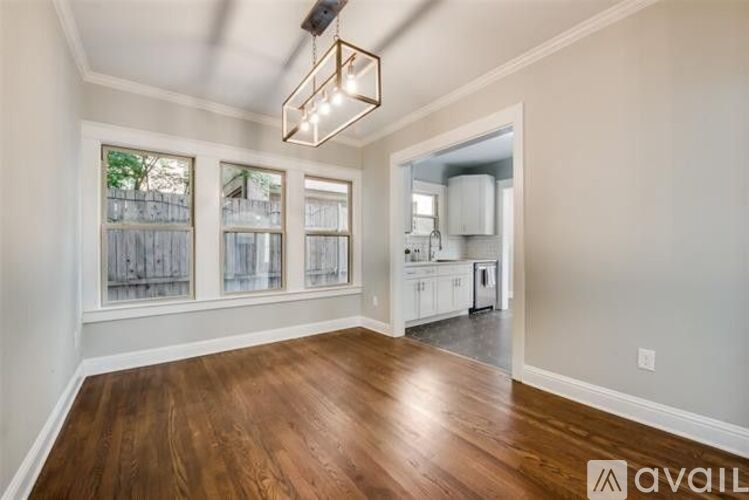 A room with wooden floors and a window with a view of a fence.
