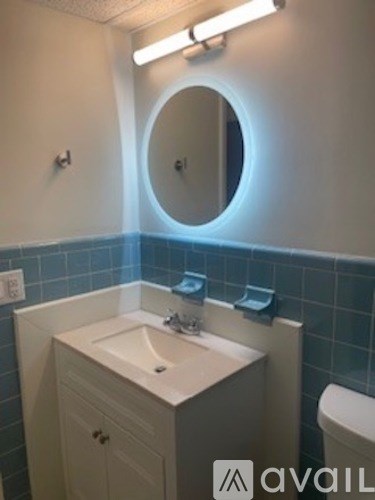 A bathroom with a sink, toilet and mirror.