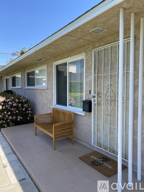 A wooden bench sits on a patio in front of a house.