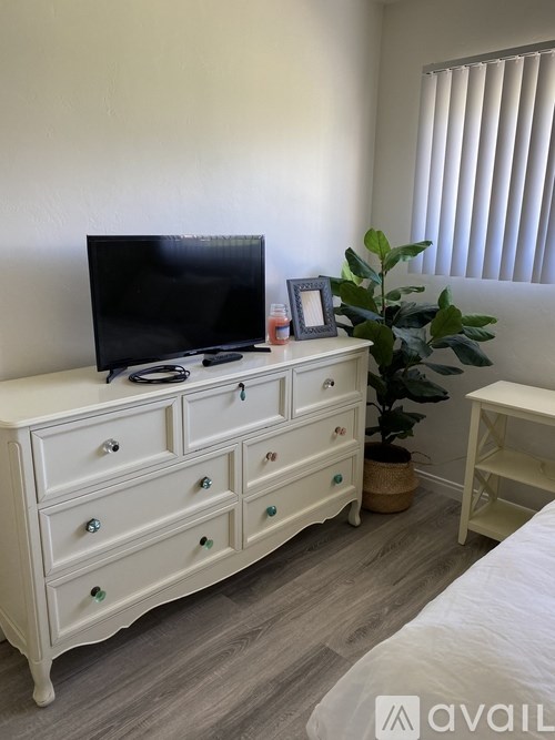 A white dresser with a flat screen TV on top of it.