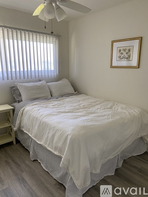 A bedroom with a bed, pillows, a ceiling fan, and a window with blinds.