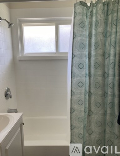 A bathroom with a white tub, sink, and shower curtain.