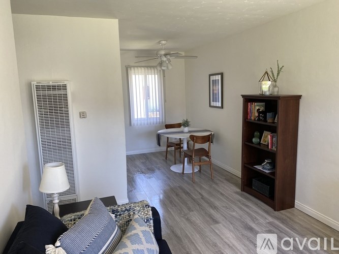 A living room with a couch, a chair, a table, and a bookshelf.