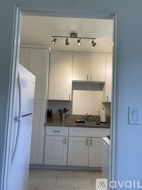A kitchen with white cabinets and a refrigerator.