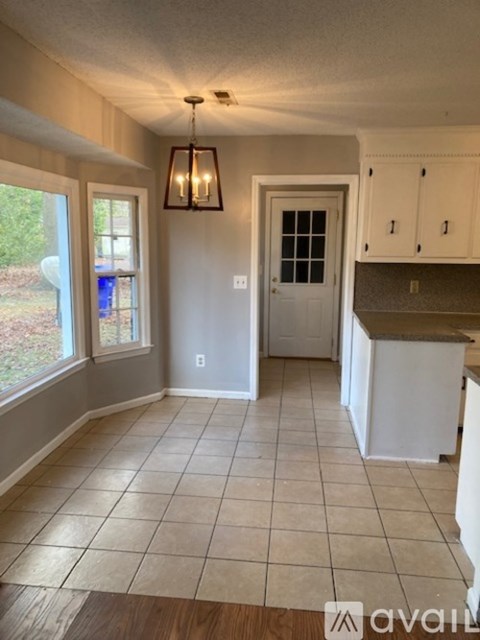A kitchen with white cabinets and a tiled floor.
