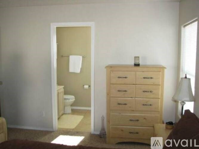 A bathroom with a toilet, a cabinet, and a doorway leading to another room.