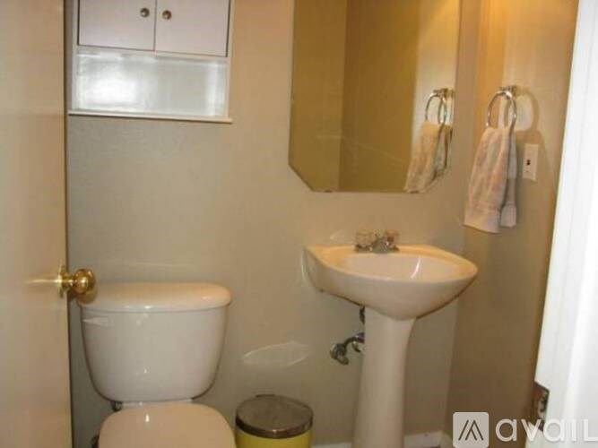 A bathroom with a toilet, sink, and mirror.