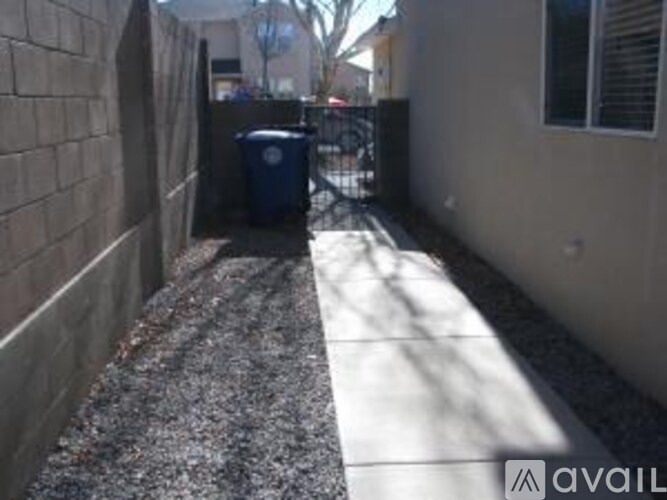 A small alley with a blue trash can and a wall on the left.