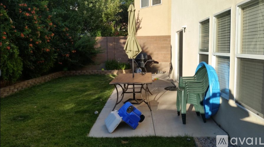 A patio with a table, chairs, and a blue cooler.