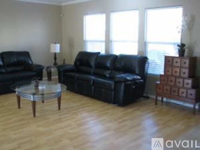 A living room with black leather furniture and wooden floors.