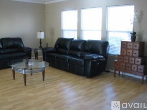 A living room with black leather furniture and wooden floors.