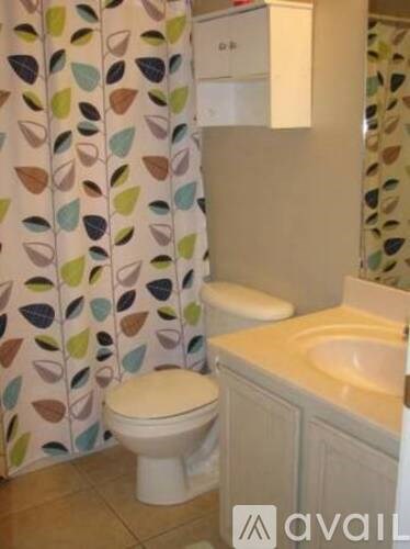 A bathroom with a toilet, sink, and shower curtain.
