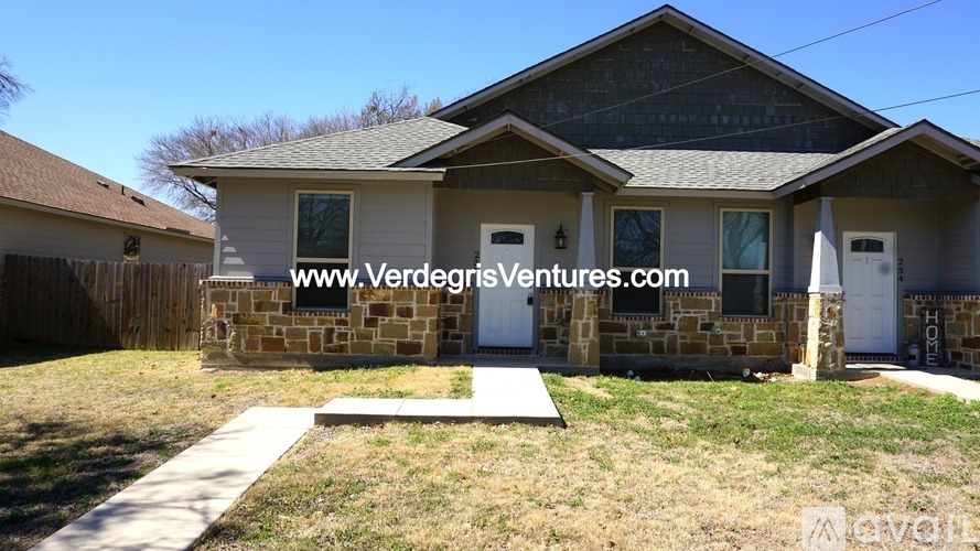 A house with a white fence and a brown roof is for sale.