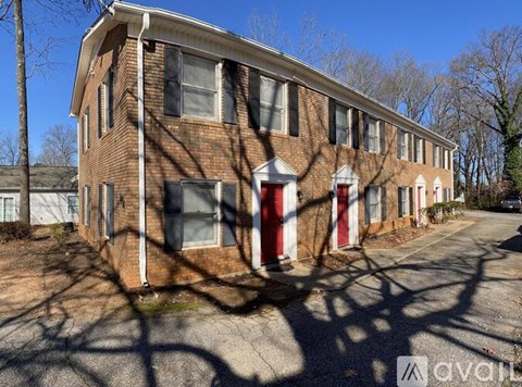 A brick building with a red door is surrounded by bare trees.