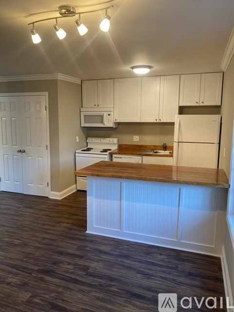 A kitchen with white cabinets and a wooden countertop.