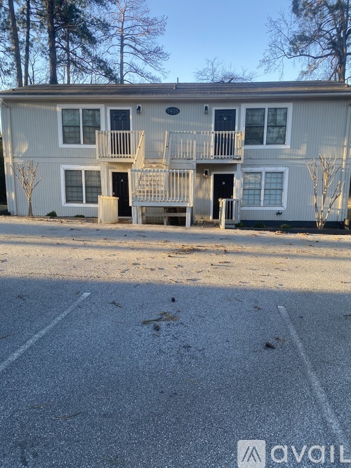 A two-story apartment building with a parking lot in front.