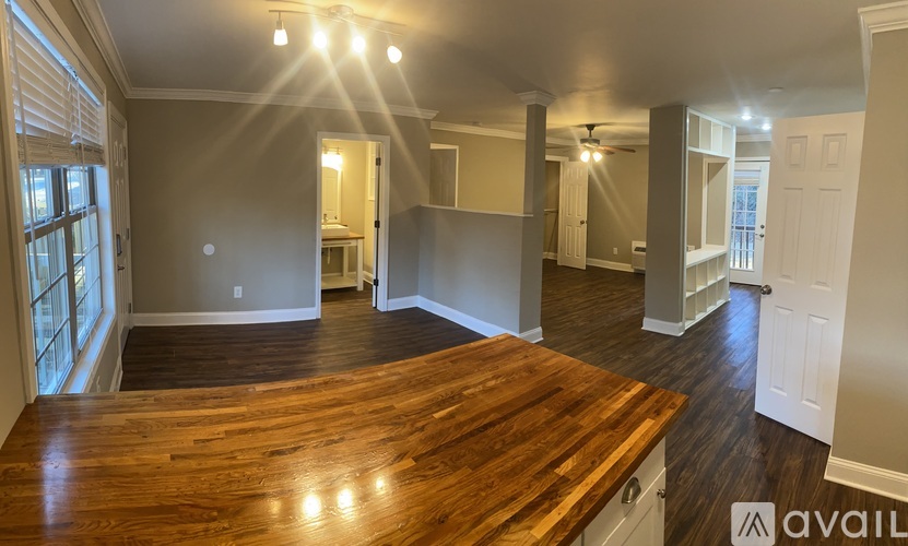 A spacious room with a wooden floor and a large window on the left side.