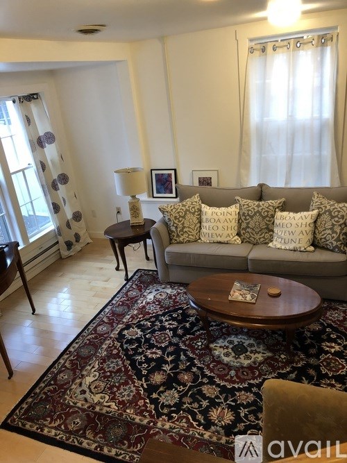 A living room with a couch, a table, and a rug.