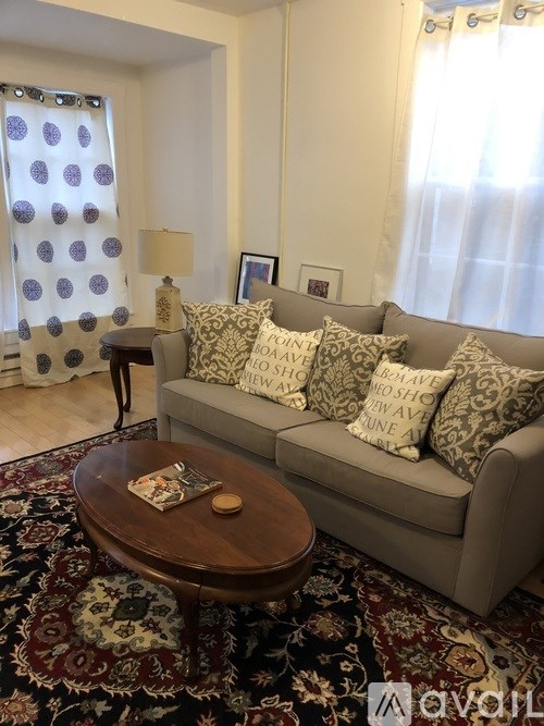 A living room with a couch, a table, and a rug.
