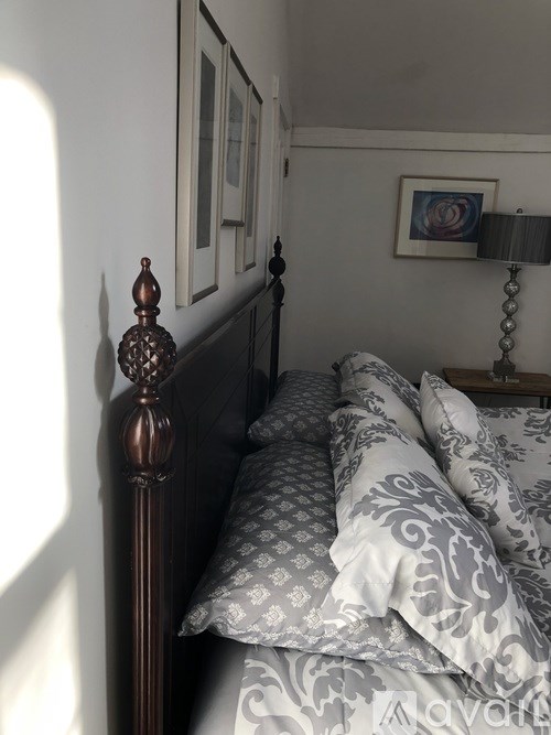 A bed with a wooden headboard and grey and white patterned pillows.