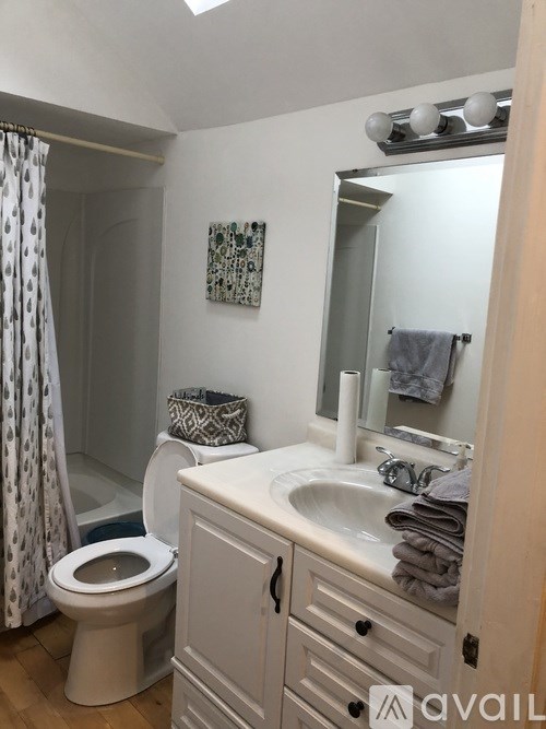 A bathroom with a toilet, sink, and mirror.