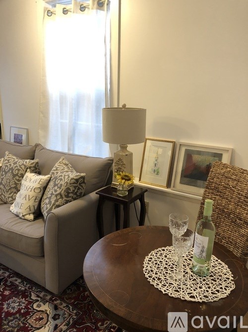 A living room with a couch, a table with a glass and a bottle on it, and pictures on the wall.