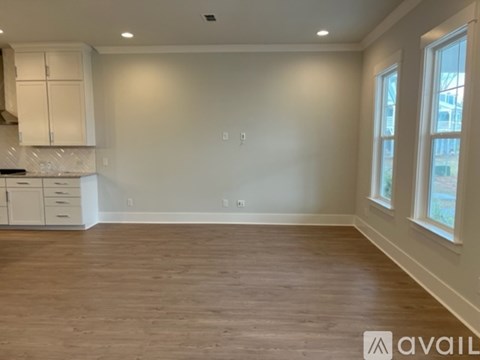 A kitchen with white cabinets and a wooden floor.