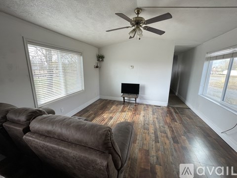 A living room with a brown couch and a ceiling fan.