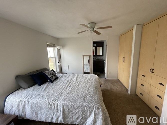 A bedroom with a bed, dresser, and a ceiling fan.