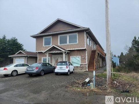 A house with a brown roof and a sign that says "AVAIL" in front of it.
