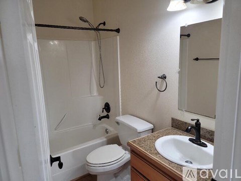 A white toilet sits next to a white bathtub in a small bathroom.