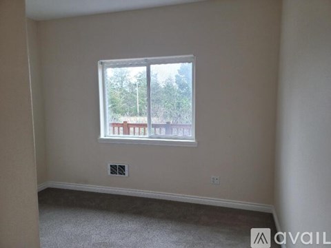A room with a window showing a view of a street with houses.